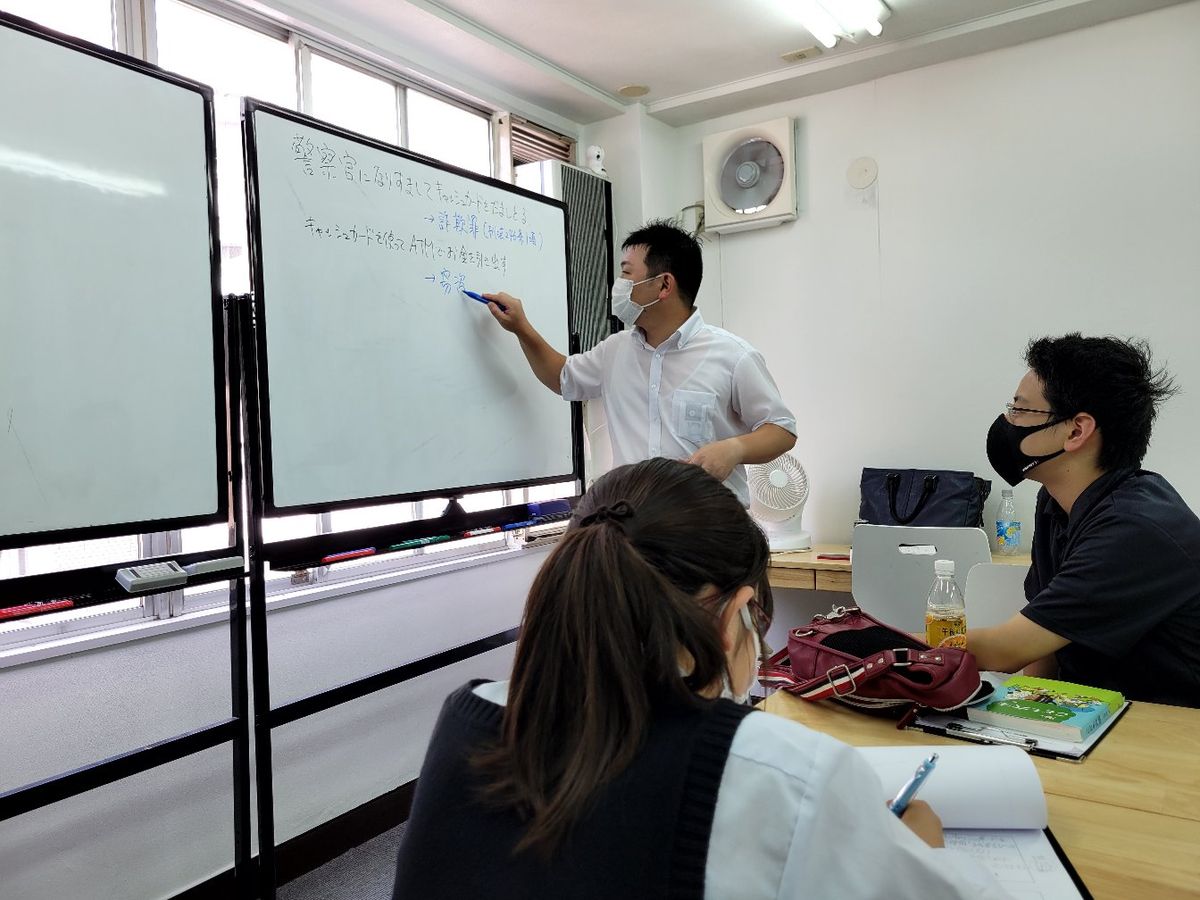 講師がホワイトボードに書き込み、生徒たちがノートを取っている授業風景
