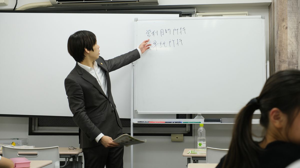 講師がホワイトボードに板書しながら授業を進める様子
