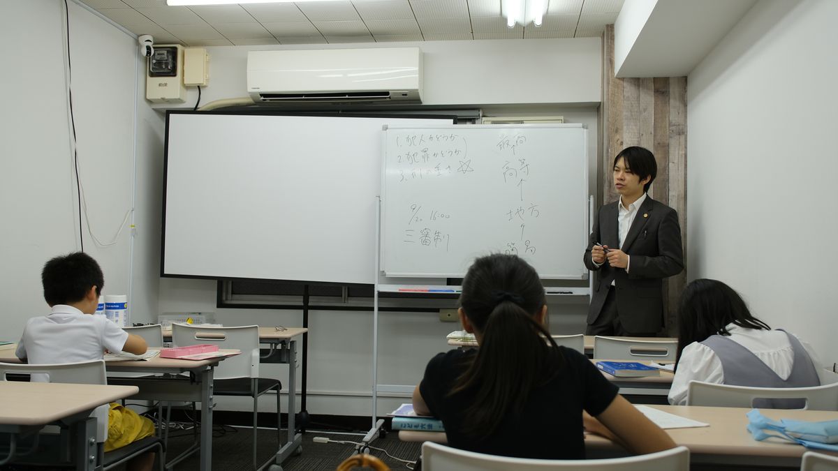 講師がホワイトボードの前で授業をし、生徒たちが聞いている教室全体の様子