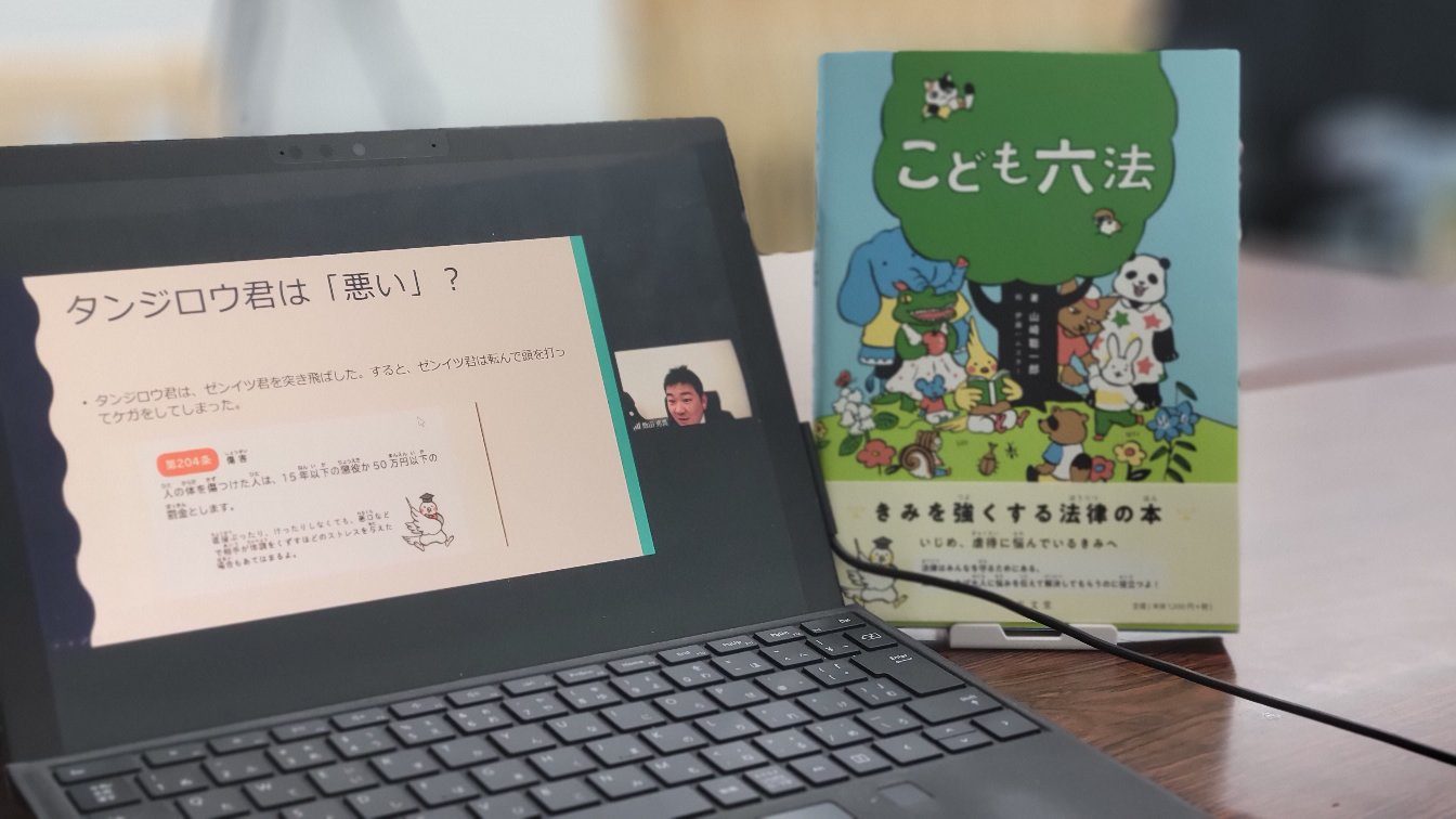 オンライン授業の受講風景。パソコンの画面に「タンジロウ君は『悪い』？」のスライドと講師が映っている