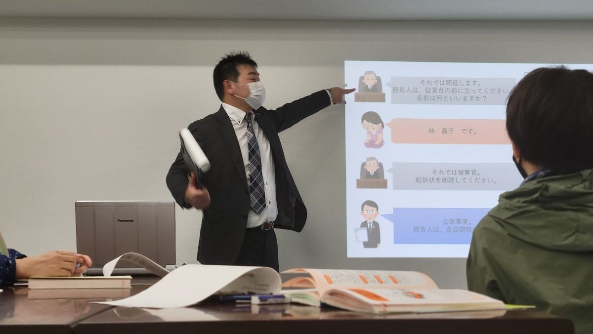 スライドを指しながら説明する講師と、資料を見ながら聞く生徒